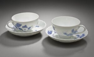 Two durable vintage porcelain teacups with blue floral relief patterns, showcasing the high-quality craftsmanship and longevity of antique teaware